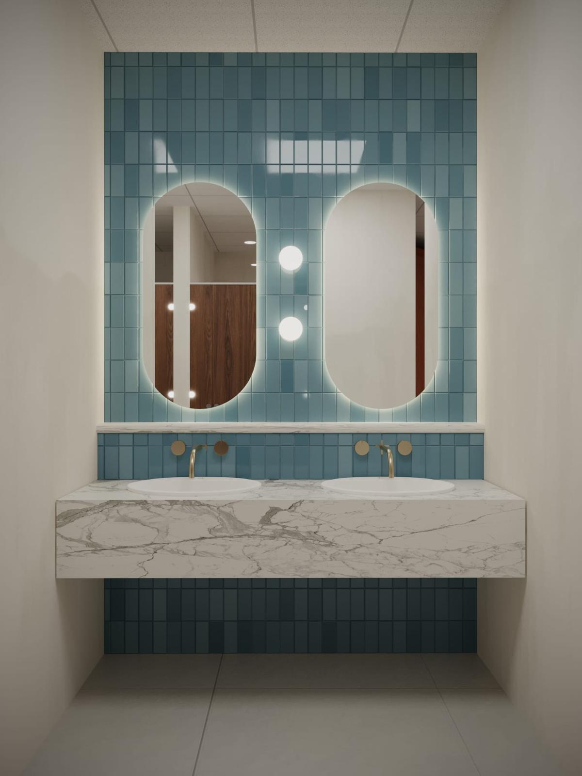 Twin backlit oval mirrors over a marble vanity with teal glazed tile
